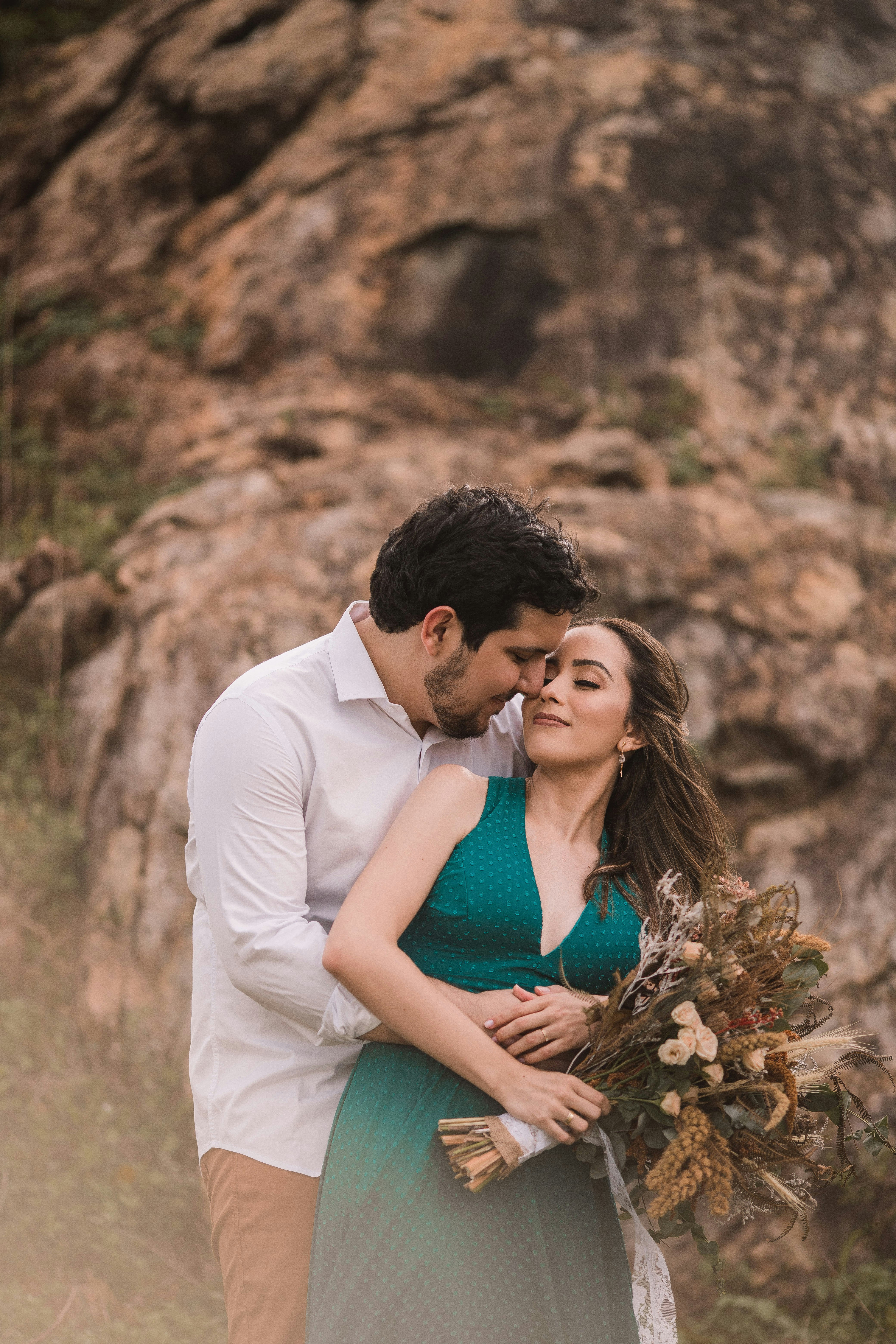 man in white crew neck t-shirt kissing woman in teal sleeveless dress